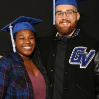 two friends in graduation caps with gvsu varsity jacket